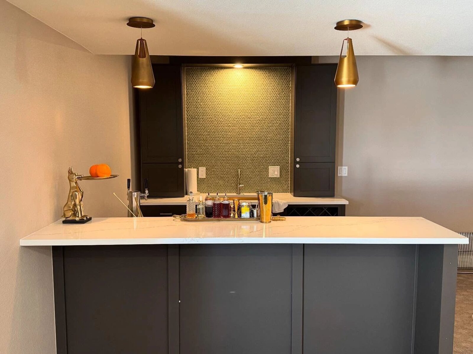 Basement wet bar with two brass cone pendant lights over the counter.