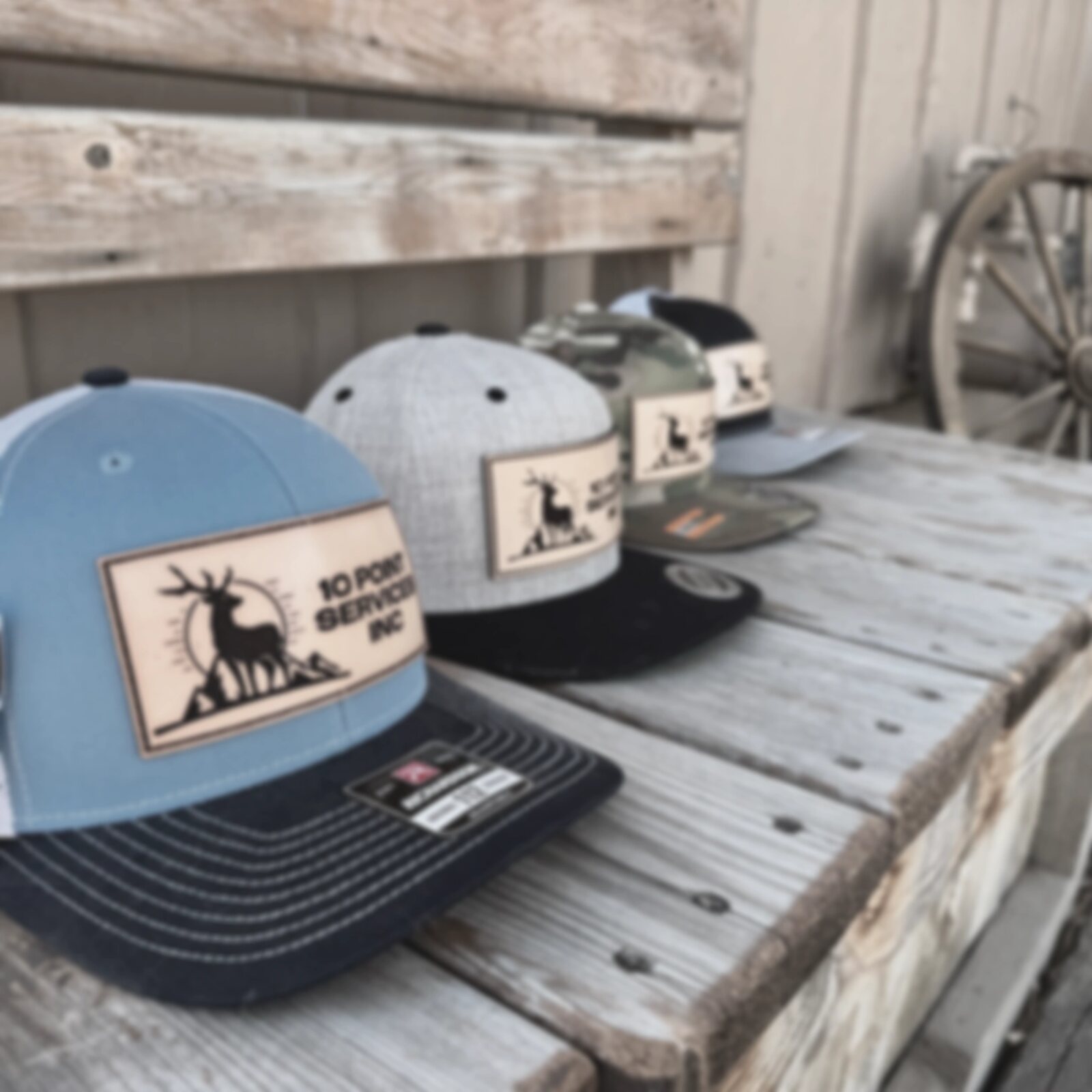 Trucker caps with the 10 Point Services elk patch on a reclaimed wood bench.